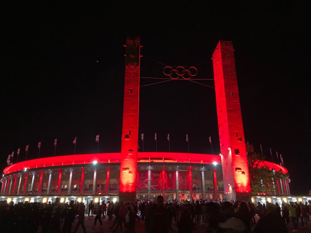 Das Olympiastadion Berlin bei Nacht, rot angestrahlt.