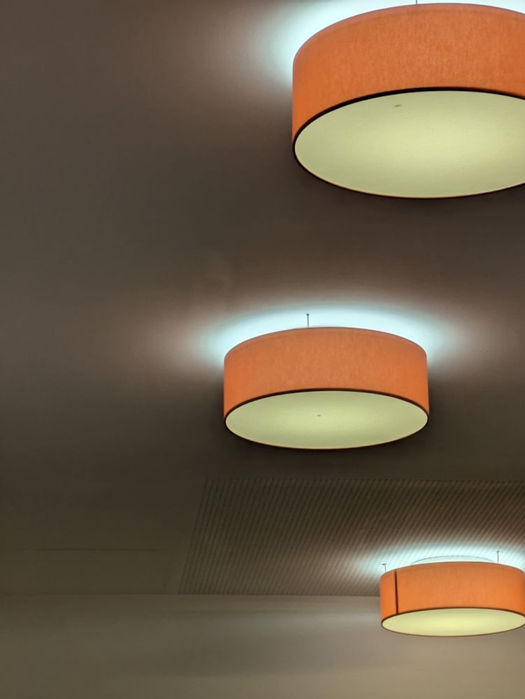 Drei orangefarbene Deckenlampen mit Lichtkreisen.
