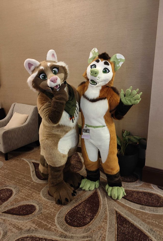 Reese(on the left)and Ren standing beside one another with Reese giving a pondering pose and Ren waving.