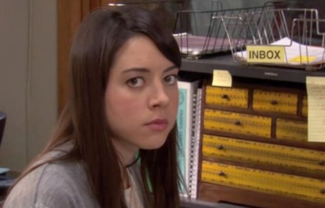 aubrey plaza as april in the tv series ’parks & recreation’. she’s doing a ‘look to camera’ joke. 