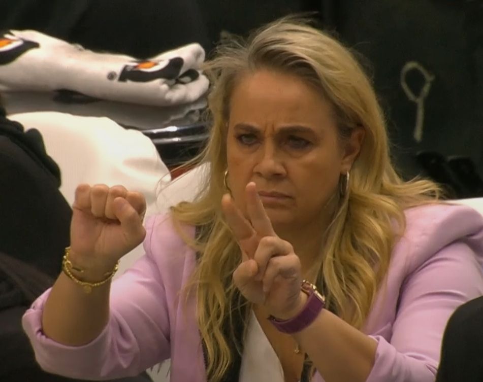 A woman holding up a fist in one hand and 2 fingers in the other hand. 