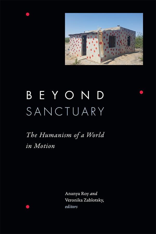 Cover of Beyond Sanctuary: The Humanism of a World in Motion, edited by Ananya Roy and Veronika Zablotsky. The cover features a photo of a small concrete building painted with red polka dots, set in an arid landscape under a clear blue sky. The house is part of an art installation by Álvaro Enciso, "La Casa de los Puntos Rojos." The image is placed against a black background with minimalist white and pale blue text. Small red dots accent the corners of the design.