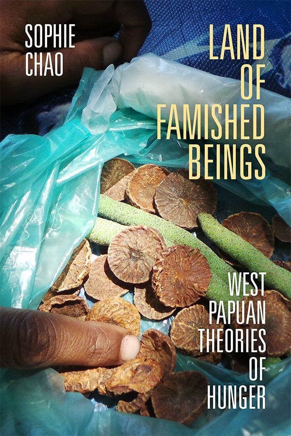 Cover of Land of Famished Beings: West Papuan Theories of Hunger by Sophie Chao. The cover features a photograph, taken by the author, of dried betel nuts in a plastic bag. The dried nuts are brown and disk shaped with a wrinkled surface. The bag also contains what appear to be green pods. A finger belonging to a person with Black skin points at the dried nuts.  
