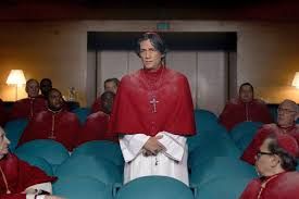 Actor Carlos Diehz playing Cardinal Benitez in Edward Berger's Conclave. He is standing in a meeting room with other cardinals, all dressed in white gown and red chasuble.
The story: "Cardinal Lawrence is charged with leading one of the world's most secret and long-standing events, the selection of a new pope, where he finds himself at the center of a conspiracy that could shake the very foundations."