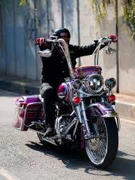A Latino man riding a purple Chicano inspired Harley Davidson