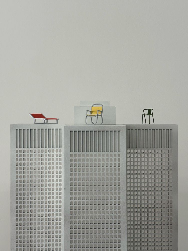 A picture of three miniature chairs atop a miniature building