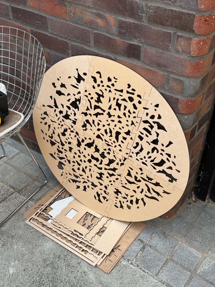 Photograph of a laser cut gobo, made of smaller parts and joined together to create an oval shaped stencil for a dappled light effect