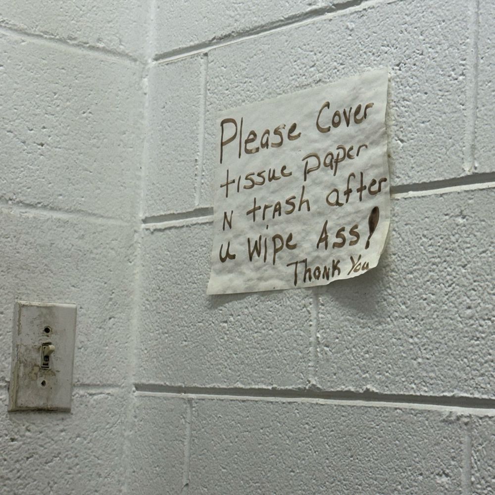 A handwritten sign in a gas station bathroom that said “Please Cover tissue paper n trash after u wipe Ass! Thank You”