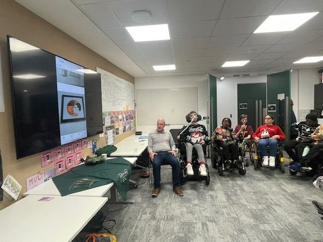 People in a room hearing and looking at Harry's work