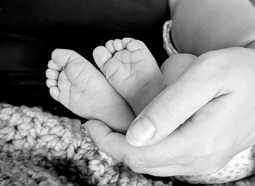 Black and white image of a mother's hand holding baby's feet