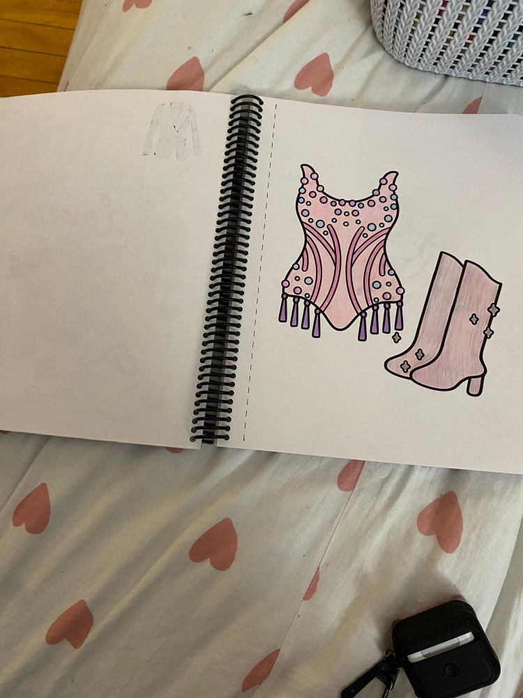 Lover bodysuit colouring page inside the coil bound book. It is coloured pink, blue, purple, and silver. 