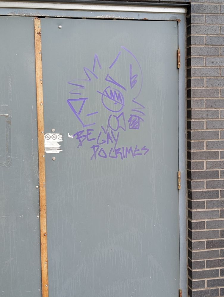 Pic of a cartoon animal drawing on a wall that says "be gay do crimes"