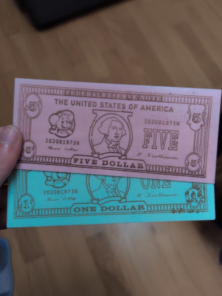 Pic of my hand holding 2 fake bank bills, a pink and a blue one. The bills are candies that looks like cardboard papers