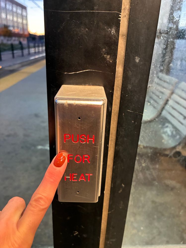Finger pushing the “push for heat” button at the light rail platform.