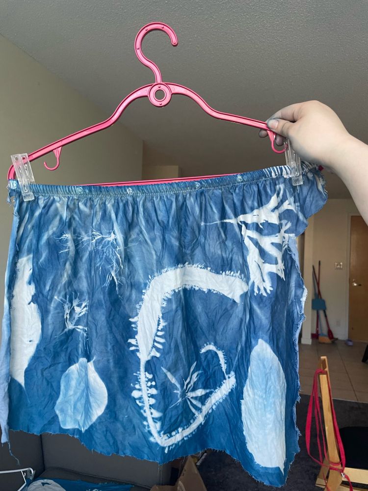 A cyanotype-printed fabric with seaweeds printed in white on the blue backgrojnd