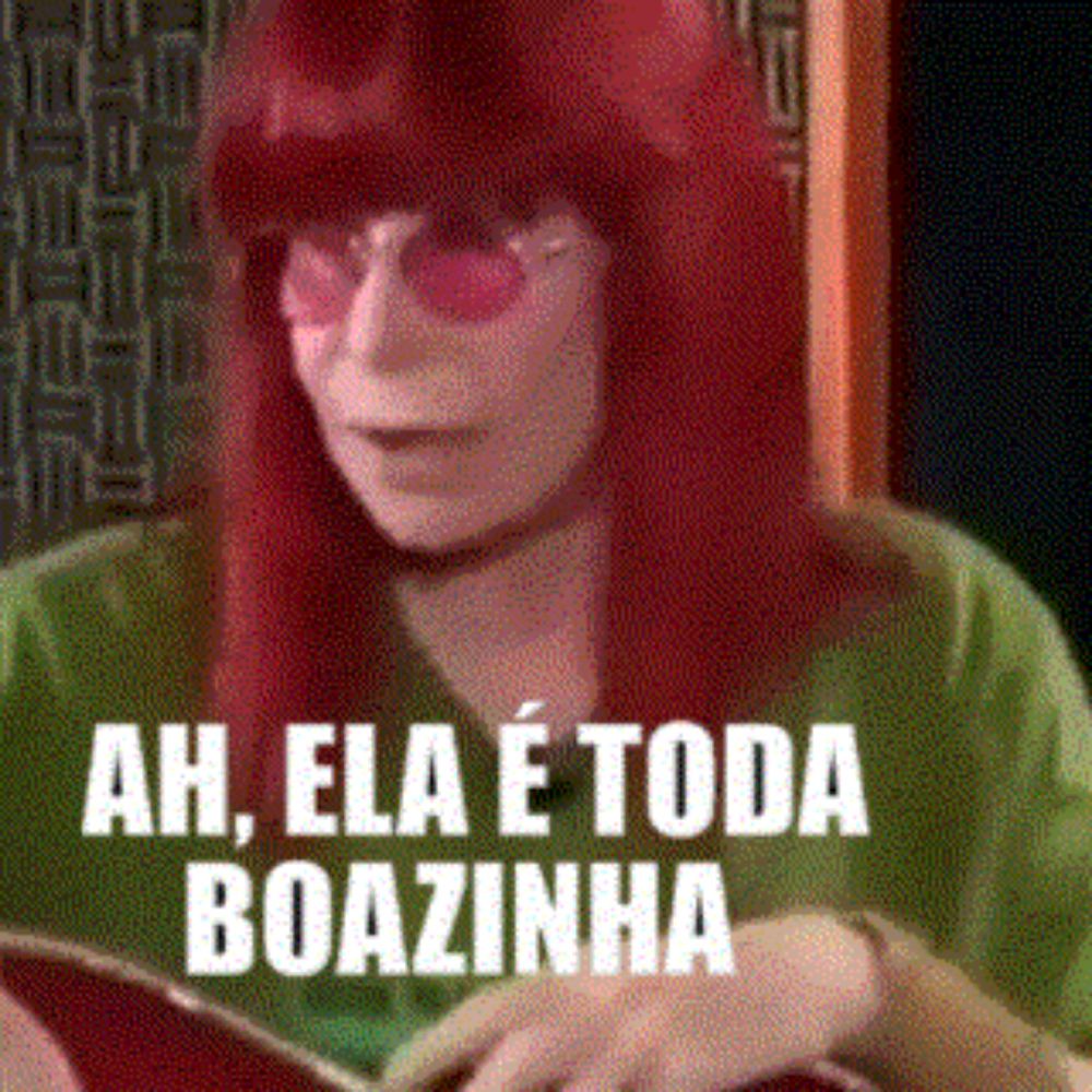 a woman with red hair and pink sunglasses is holding a book and says ah , ela e toda boazinha .