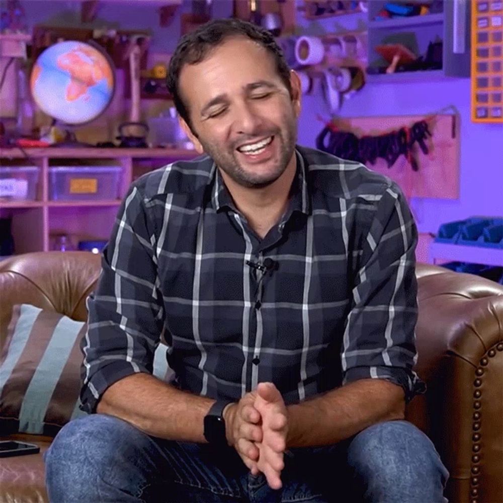 a man in a plaid shirt sits on a leather couch with his eyes closed