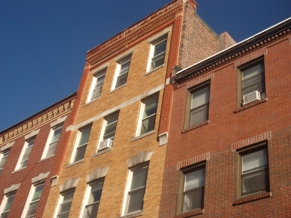 Detail of the tops of three different, well-kept brick buildings in Boston. Each boasts a unique style of ornamentation. 