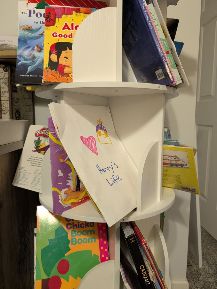 A child-made book about Henry Halfhead sits on a bookshelf with other children's stories. 