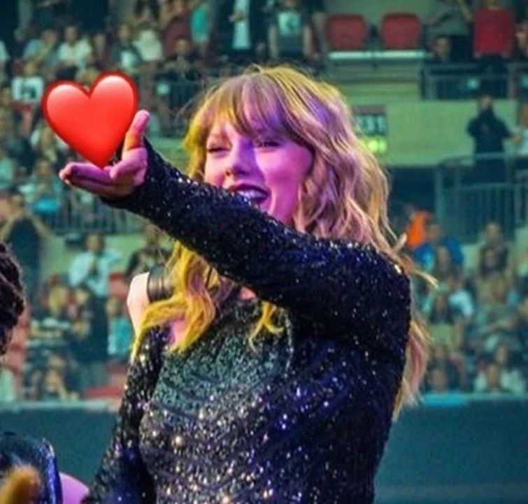 Taylor swift holding a heart emoji 
