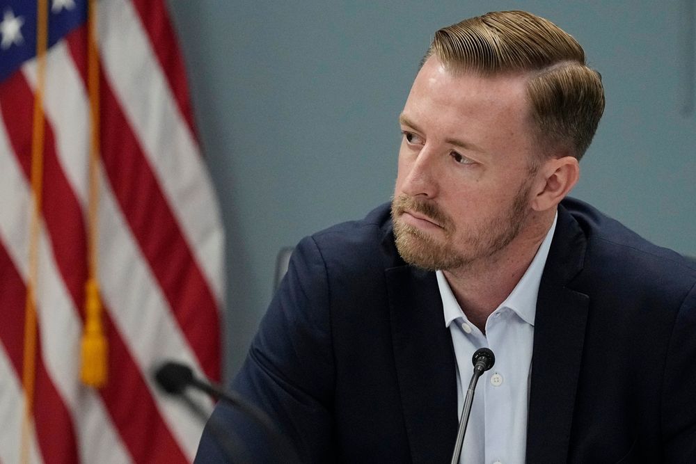 A preliminary investigation into Ryan Walters suggests a technical glitch led to an inappropriate movie auto-playing during a closed-door board meeting, but tensions remain high.