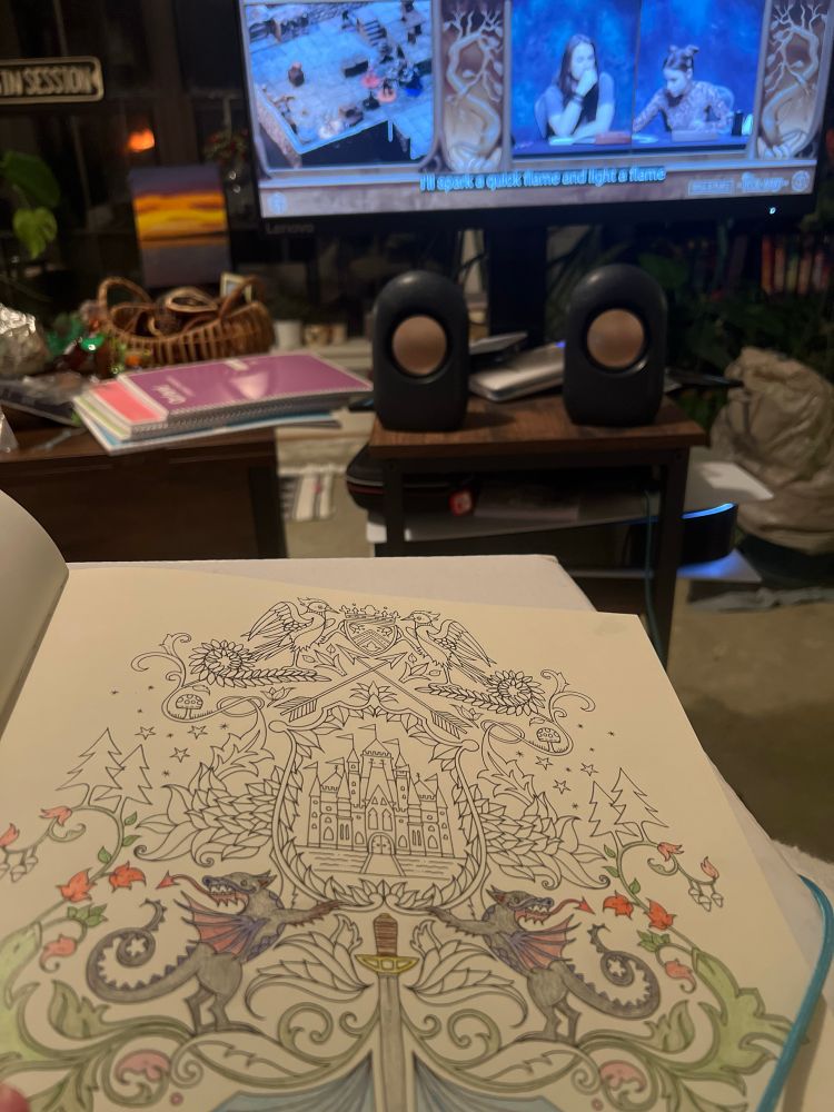 An adult Enchanted Forest coloring book. A quarter colored in, with Critical Role Exandria Unlimited in the background