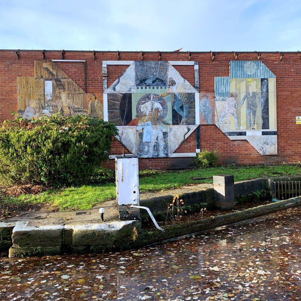 A mural depicting people in different settings set on a brick wall near a canal.