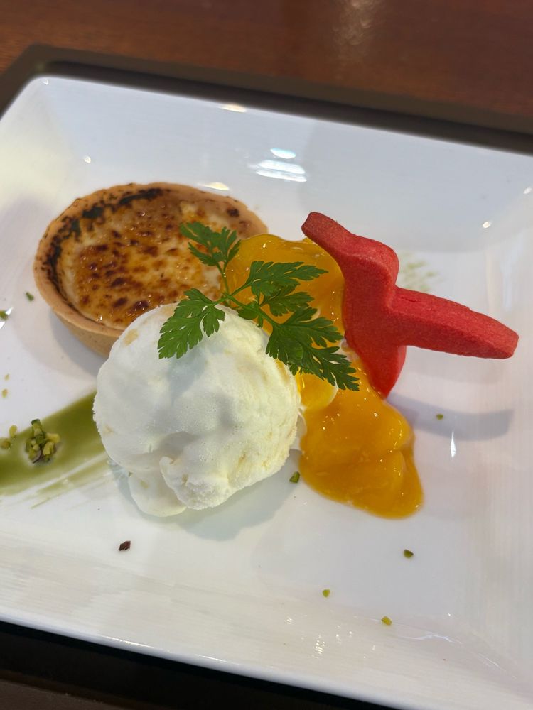 東京都美術館　田村一村展　コラボメニューのブリュレタルト ～ココナッツ&パインのアイス添え～　タルト生地に入ったブリュレと、ココナッツとパインのアイスクリームと、マンゴーのソース、アカショウビンという鳥をイメージした真っ赤なクッキーが乗っている