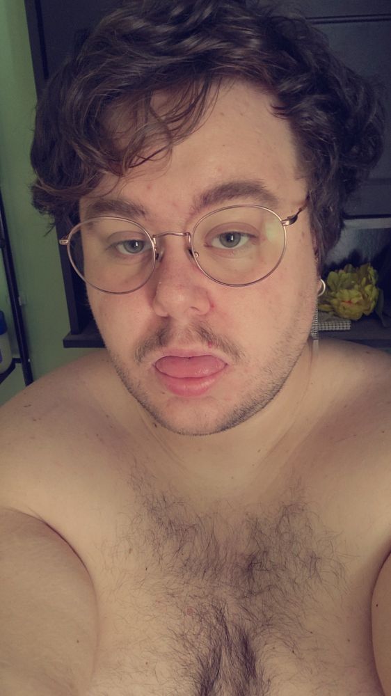 selfie of me; a plus size non-binary person with a moustache, chest hair, pink glasses, and curly brown hair