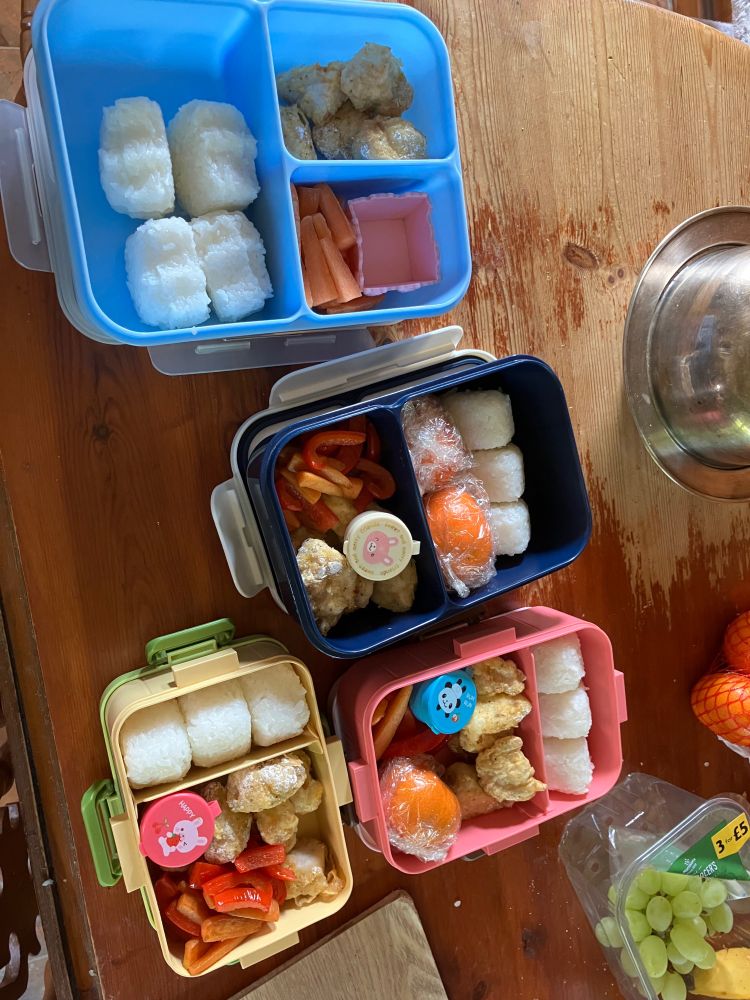 A photo of bento boxes with rice balls and other food in them. 