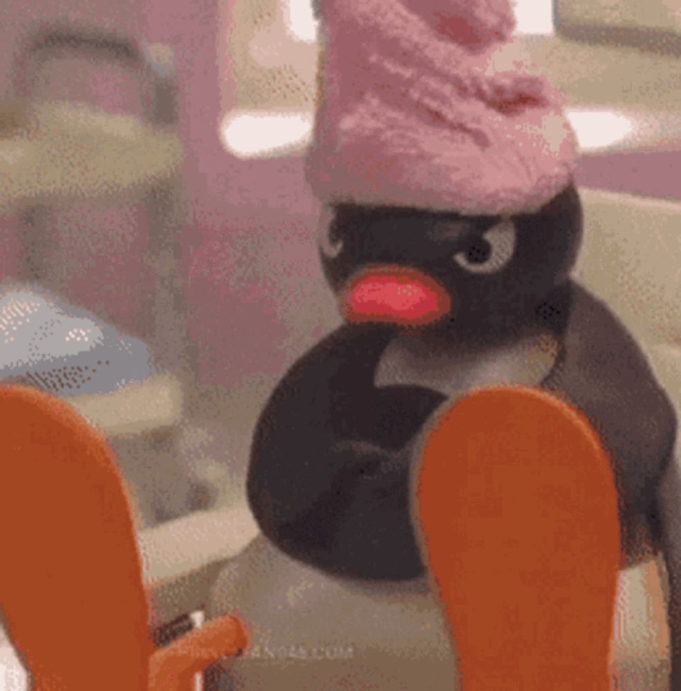 a stuffed penguin with a pink hat on is sitting on a toilet .