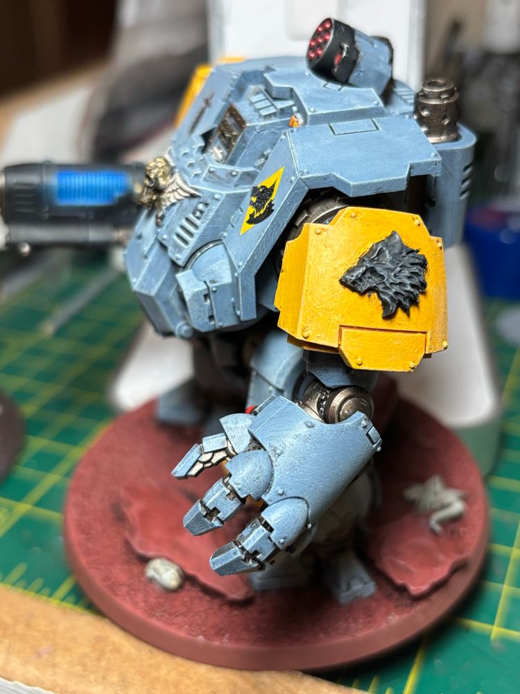 Side view. Space Wolves Redemptor Dreadnought. Yellow shoulder pads and grey armour. With a white knee pad and a yellow knee pad. A Plasma cannon on one arm and a flamer under the fist. 