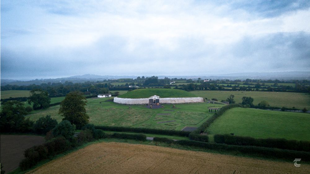 Aerial view of Newgrange Passage Tomb in the Boyne Valley, early in the morning. A light mist and low cloud hangs over the monument and surrounding fields.