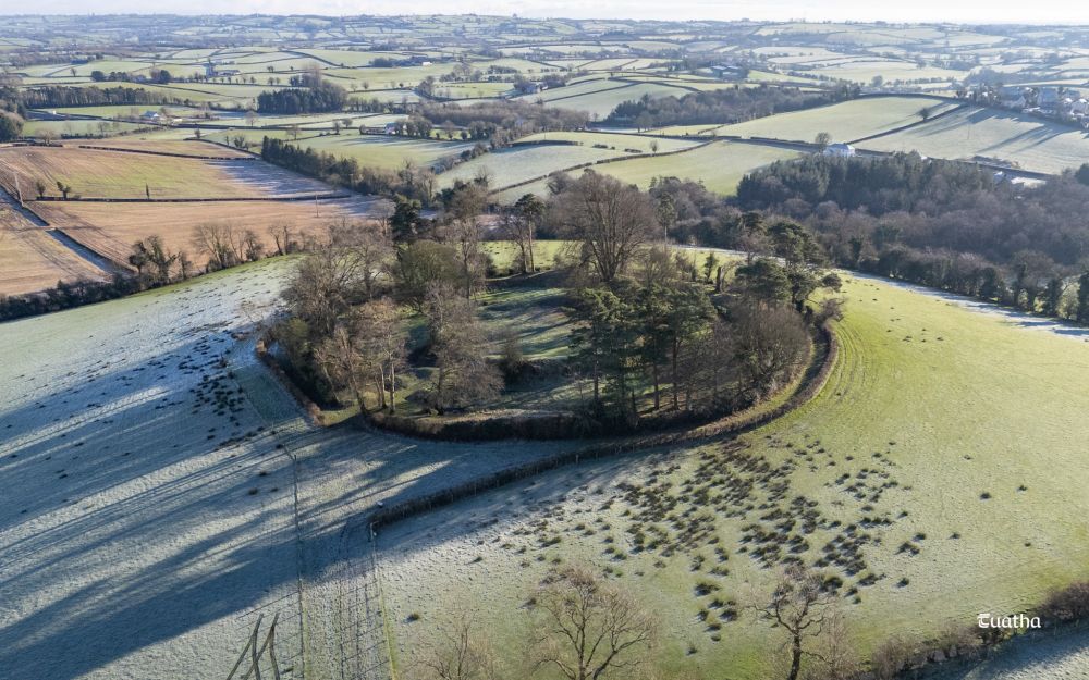 An aerial view of a large set of circular earthworks atop a frosty hill in the foothills of the Sperrin Mountains