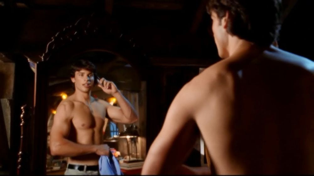 Tom welling from Smallville with a shirt holding a phone in his barn 