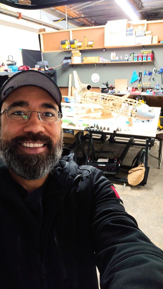 Terrance smiling in the RC CAD workshop with L-1011 RC Airplane frame in the background.