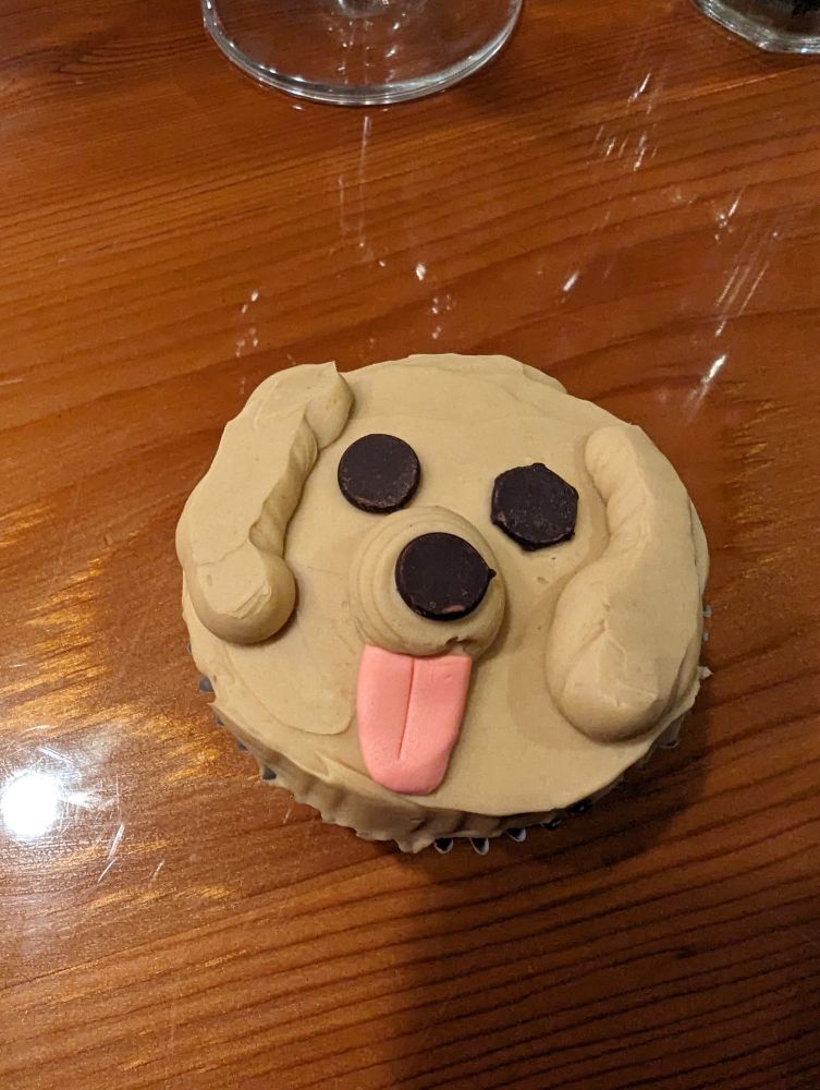 A cupcake with icing that is made to look like a dog's face. It's very cute.