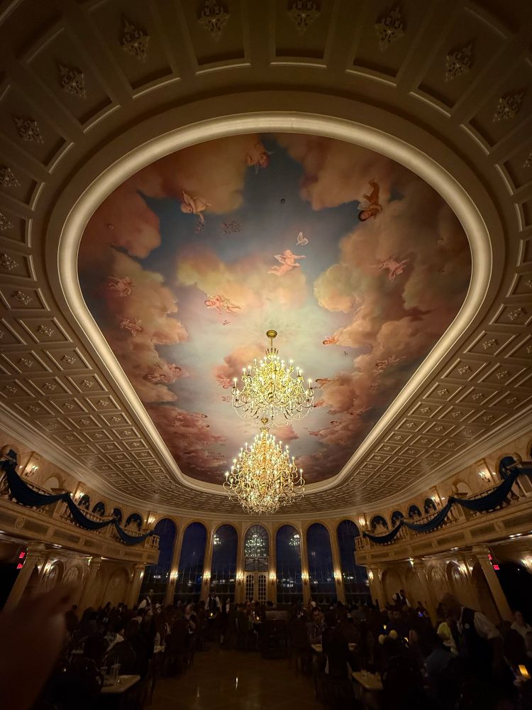 Ceiling of be our guest at magic kingdom. Sky painting with angelic babies and multiple gold chandeliers 