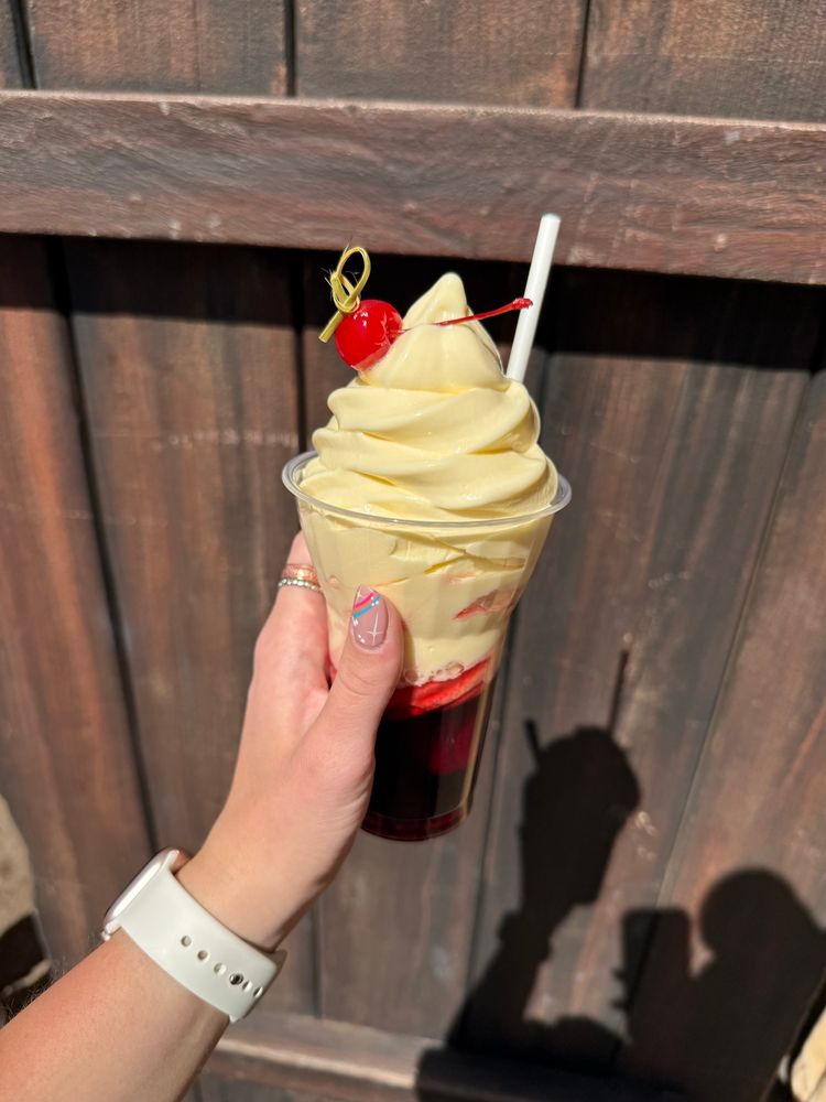 Sangria dole whip float. Red base with yellow ice cream like on top. In front of wooden door