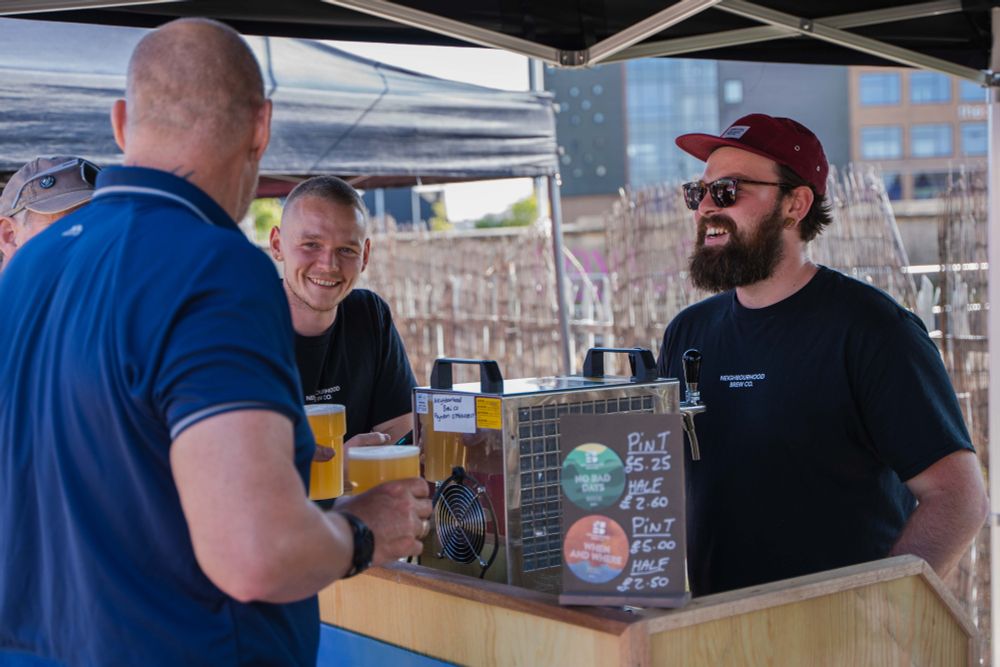 Photo of a pint of people getting a craft beer at a beer stall in Future Yard's outside space.