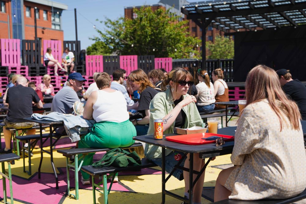Photo of groups of people sat in the sun enjoying beers at a beer festival in Future Yard's outside space.