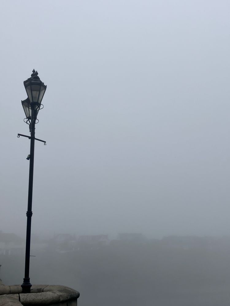 Photograph of an old-fashioned street lamp against a background of mist. Just lots of mist. 