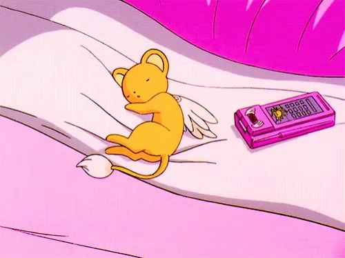 a cartoon cat is sleeping on a bed next to a pink cell phone