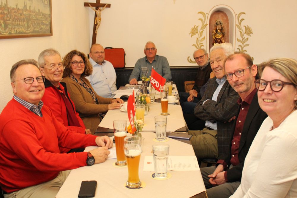Mitgliederversammlung im Klostergasthof Andechs. Mehrere Leute sitzen am Tisch und schauen in die Kamera. 