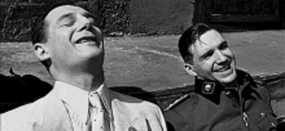 a black and white photo of two men laughing .