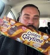a well groomed man holding up a "golden gaytime" ice cream bar