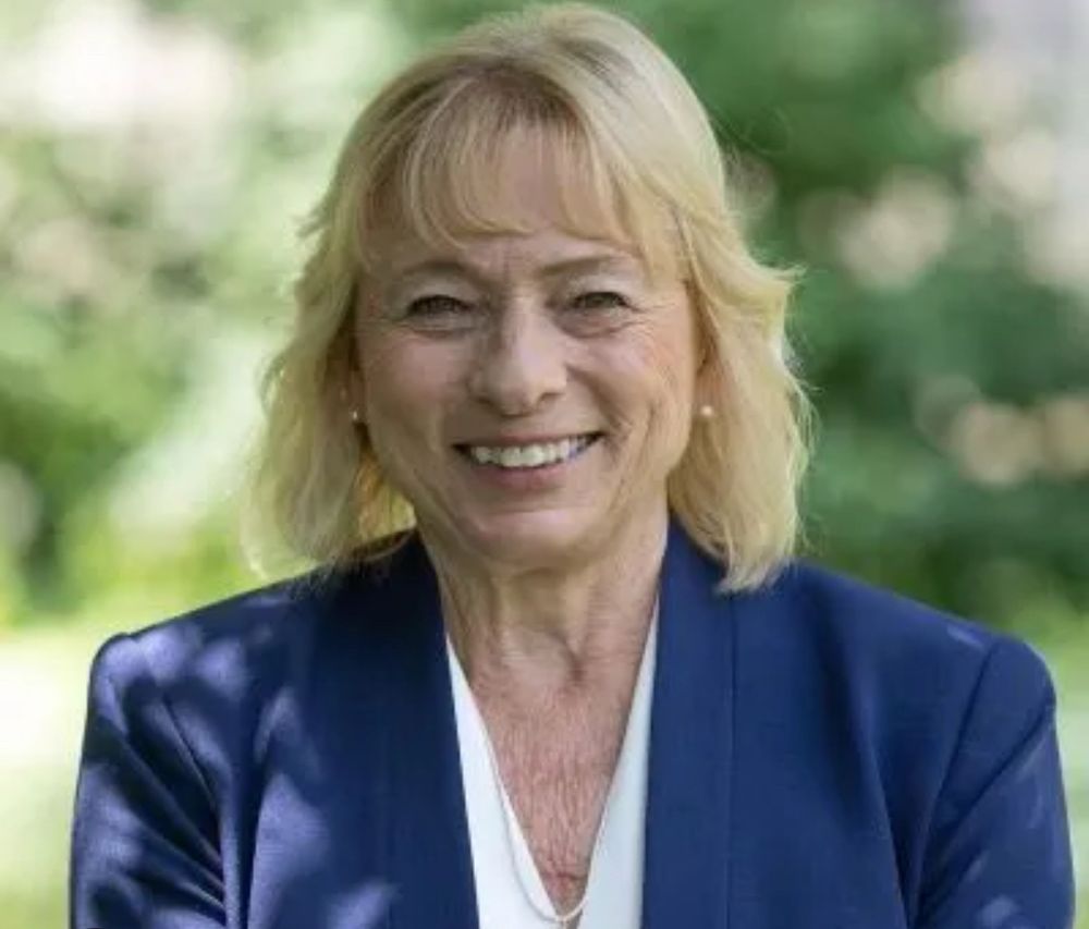 A photo of smiling Maine Governor Janet Mills against the backdrop of the state’s lovely greenery.
