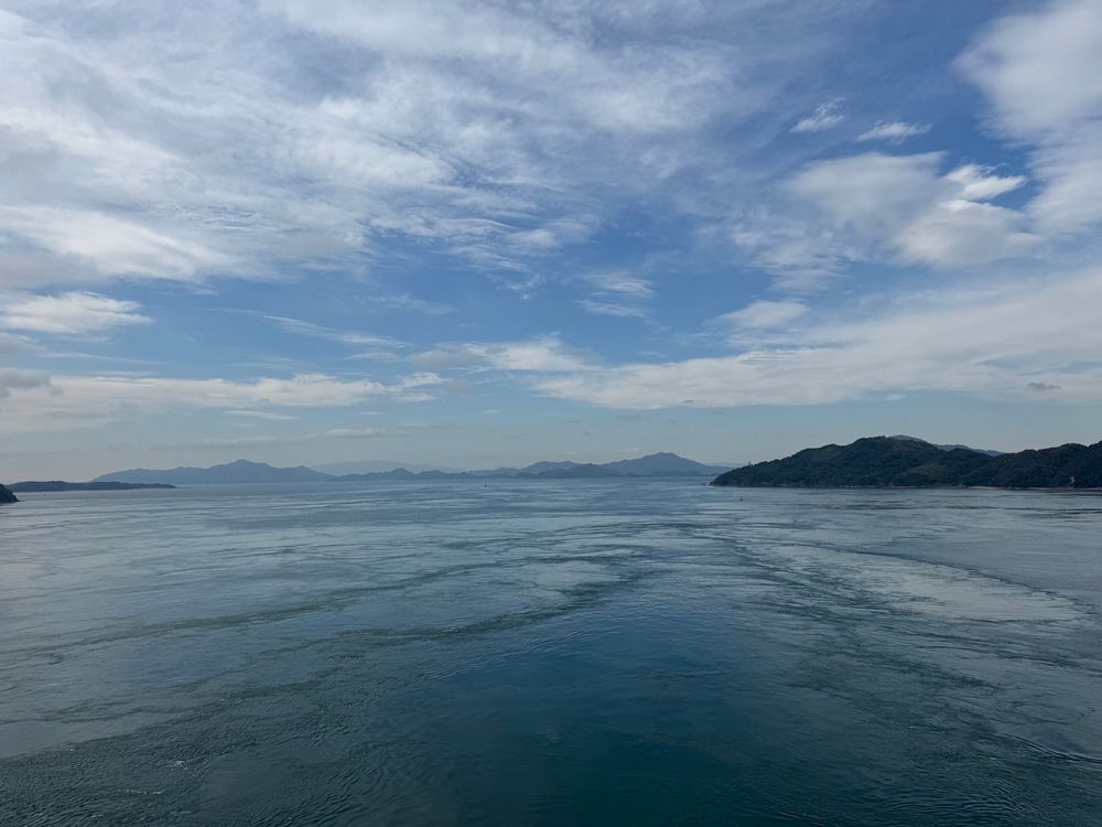 Blue sea and blue sky with windblown white clouds and distant islands 