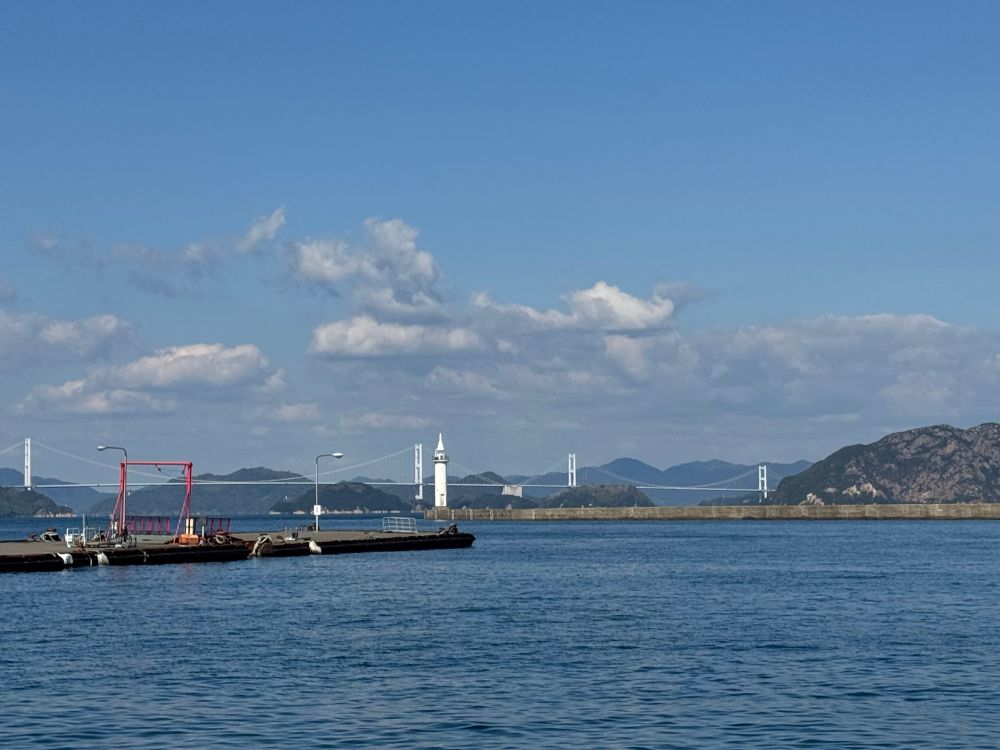 View across a sunlit bay with a white bridge swooping across to the next island 