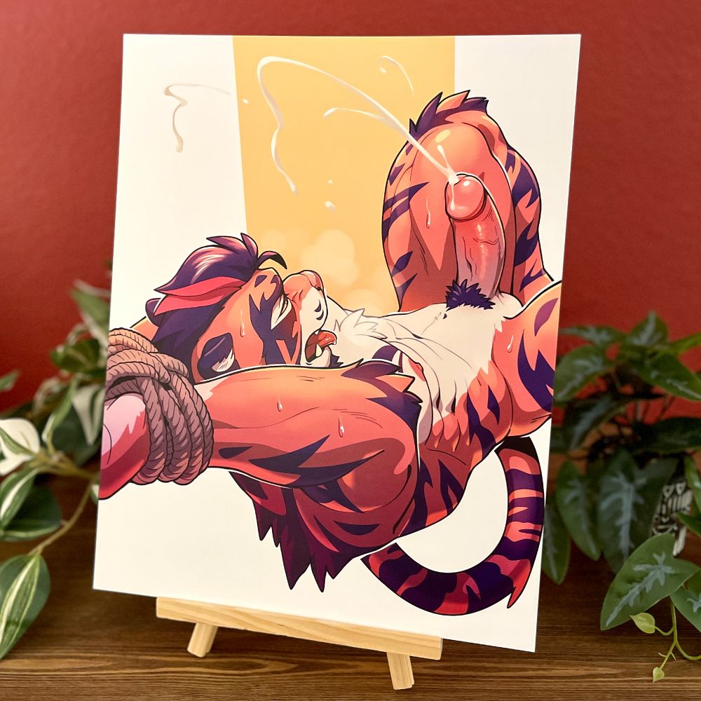 A photo of an 11 x 14 inch art print on an easel with foliage behind it, of Yakitora tied up and cumming.